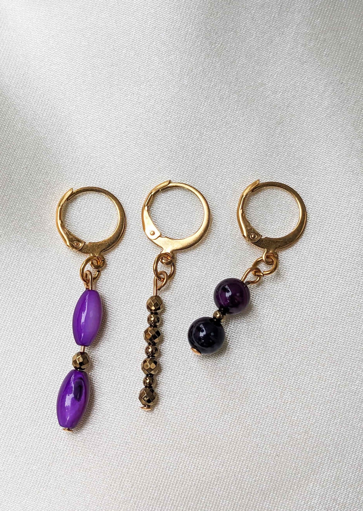 Ensemble de 3 boucles d'oreilles violettes et argentées. Composition unique avec de l'agate violette, des perles de nacre grain de riz et des hématites argentées. Le tout en acier inoxydable doré.